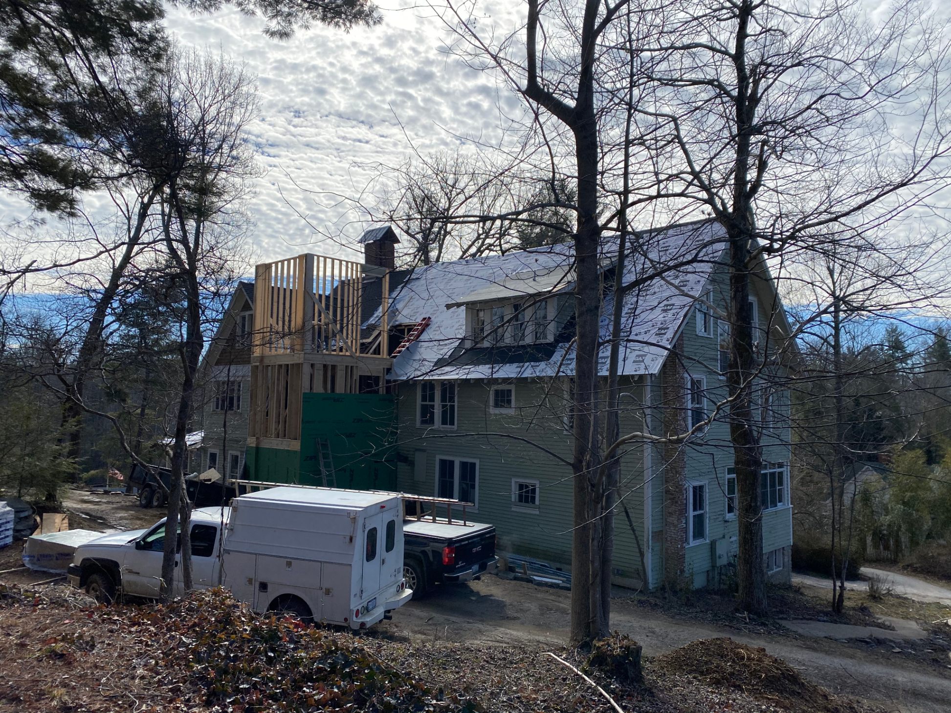 Exterior mid-renovation — new addition framing & work crews on site