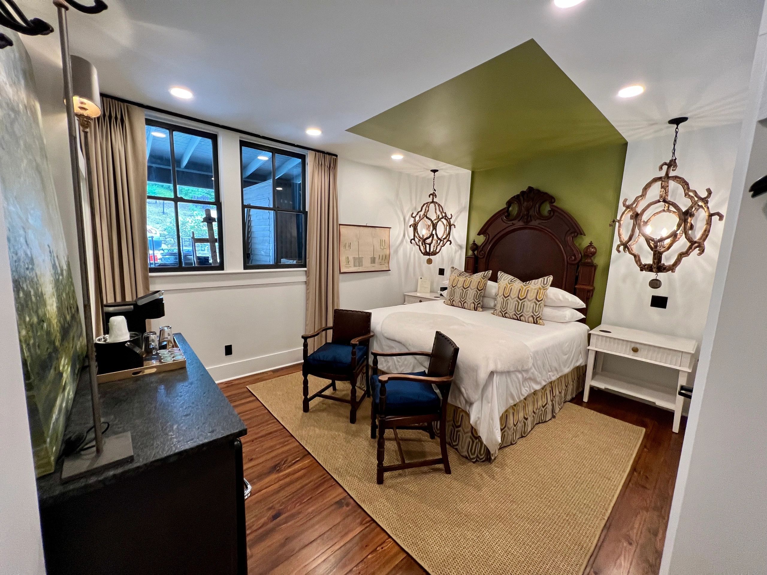 Bed with ornate dark headboard against olive-green accent wall