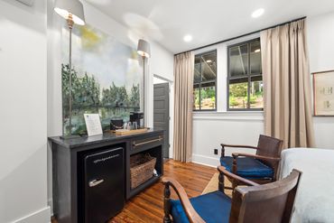 Cozy room corner with wooden chairs, black cabinet, and nature-themed wall mural
