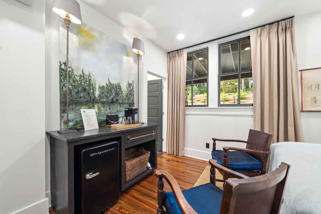 Bedroom corner with mural, brass sconces, and blue-cushioned chairs