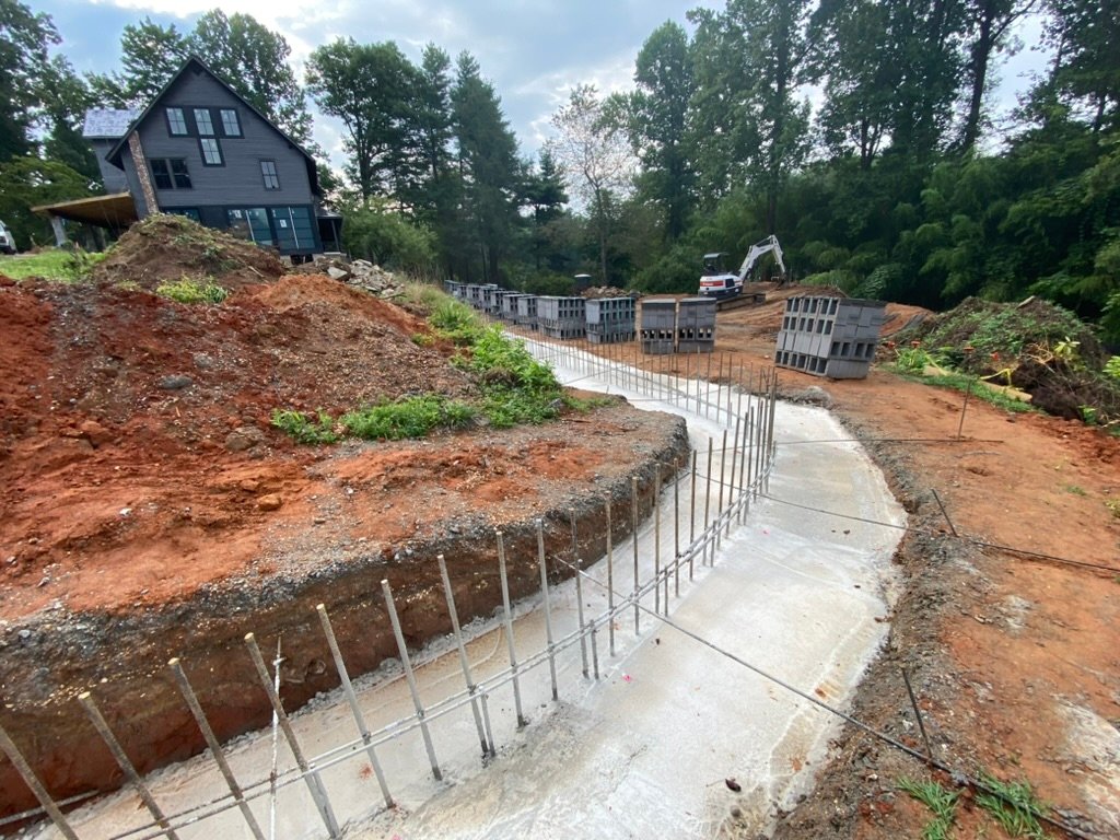 Footing pour — rebar set and concrete footings curing along the terrace line